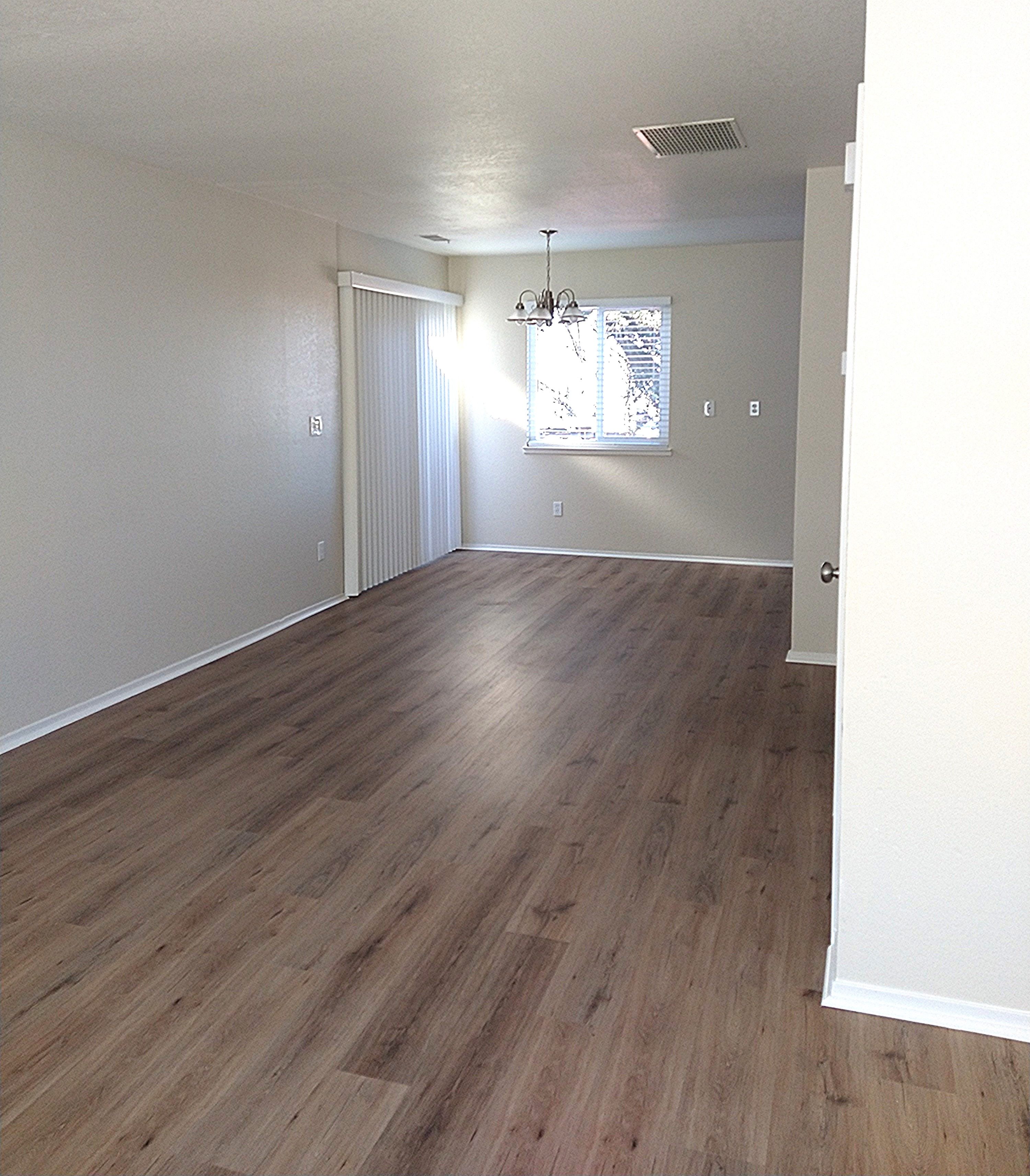 A room with wooden flooring and a window with blinds.